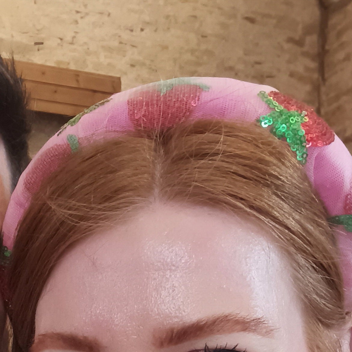 Pink headband with strawberry embellishments worn by creator.
